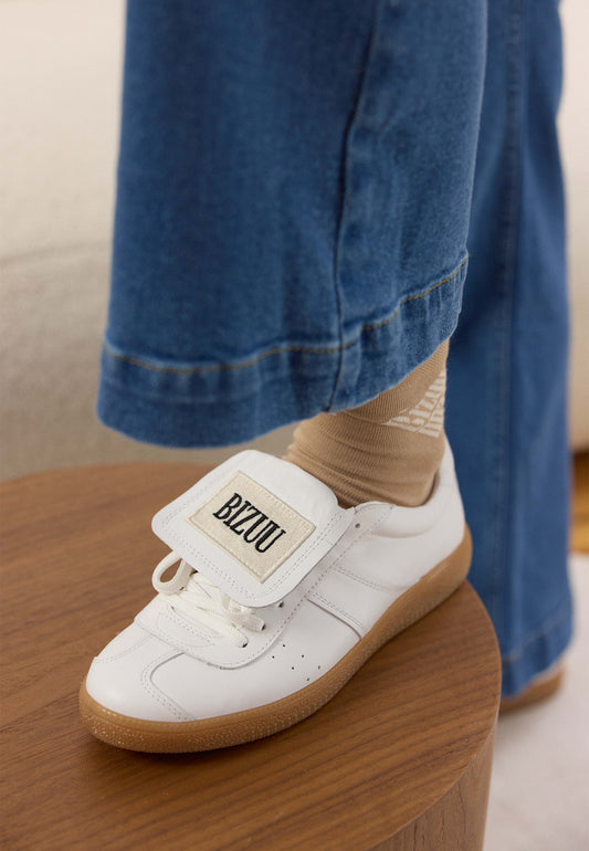 White sneakers with a rolled tongue and BIZUU MOBBY patch