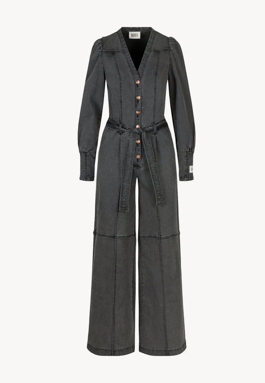Dark gray denim jumpsuit with long sleeves, wide legs, and buttons down the front. Tied at the waist with a belt.