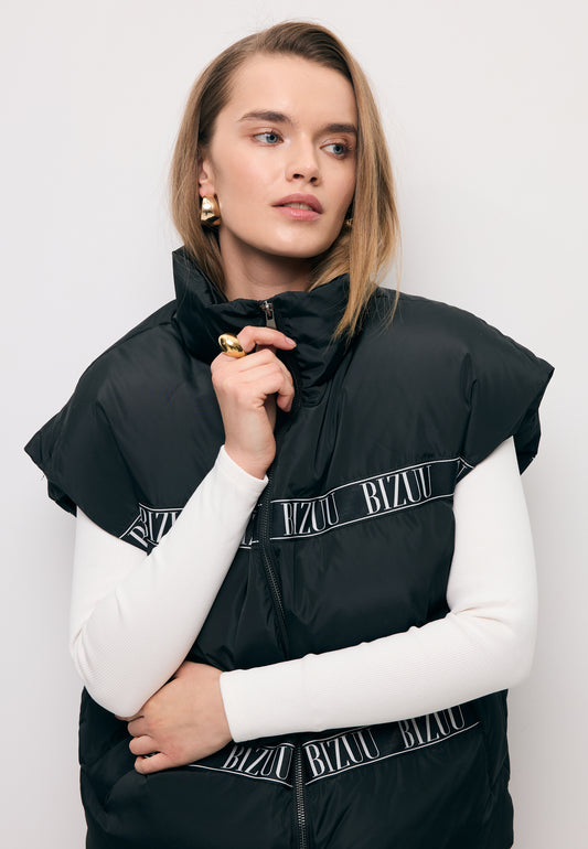 Close-up of the model fastening a black AYASE down vest with branded tape.