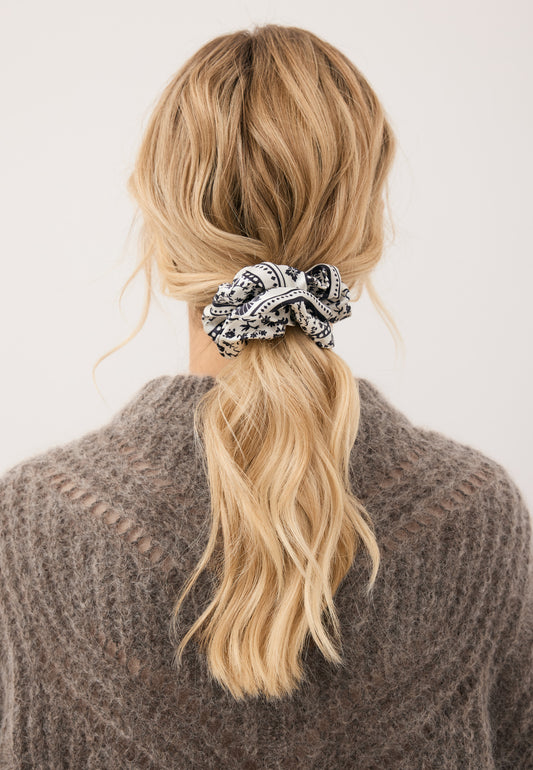 Close-up of the model’s hair tied with the BANDI silk scrunchie featuring a black floral print.