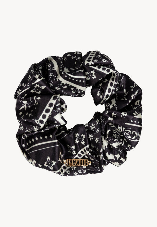 BANDI silk scrunchie with white floral print on a black background.