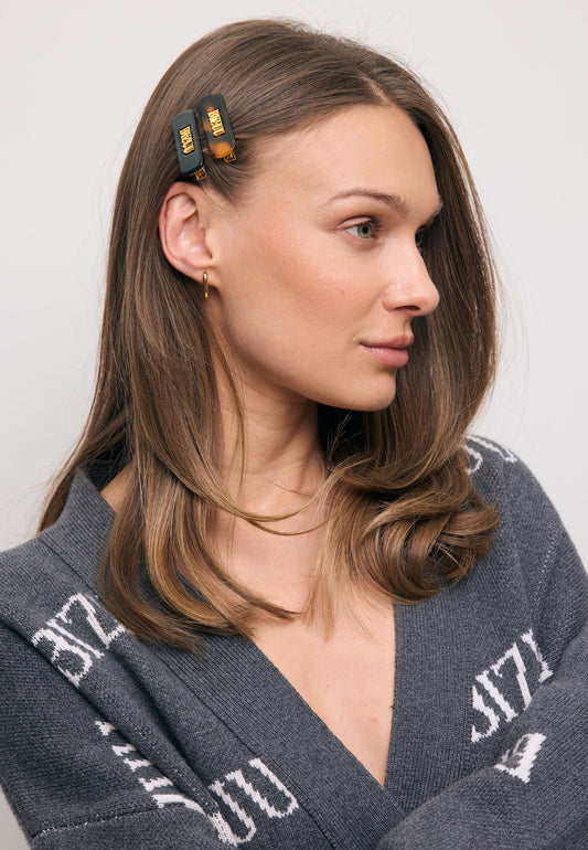 Close-up of the model’s hair styled with small CATTA clips in black and brown.