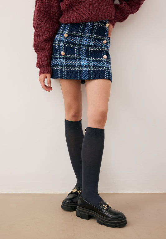 Close-up of the model’s legs wearing the DISSA navy check mini skirt, SCHOOLI knee-high socks, and LESOTHO shoes.