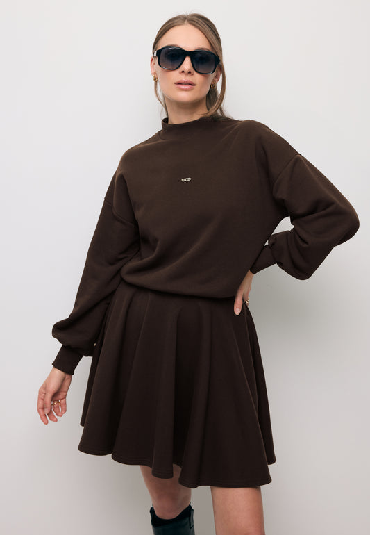 Close-up of a model wearing the brown FOXI knit dress with a flared hem.