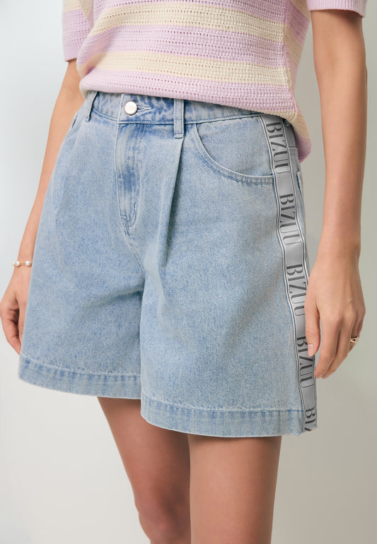 Close-up of the MIREYA denim shorts with a logo tape on the side.