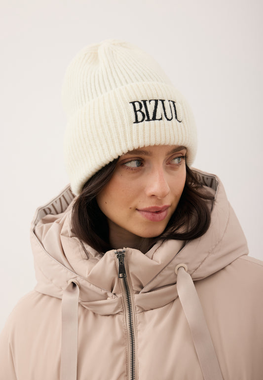Close-up of the model wearing the cream ROYU merino wool beanie with a black embroidered logo.