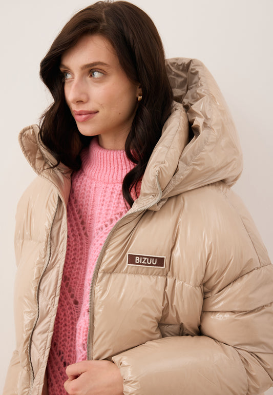 Close-up of the model wearing the beige SANYA puffer jacket made of glossy fabric.