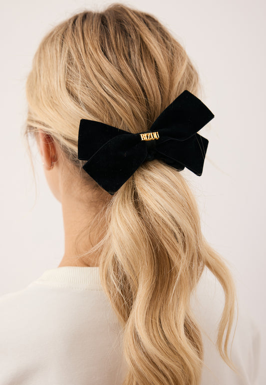 Close-up of the model’s hair styled in a ponytail with the black VELOURA scrunchie featuring a bow.