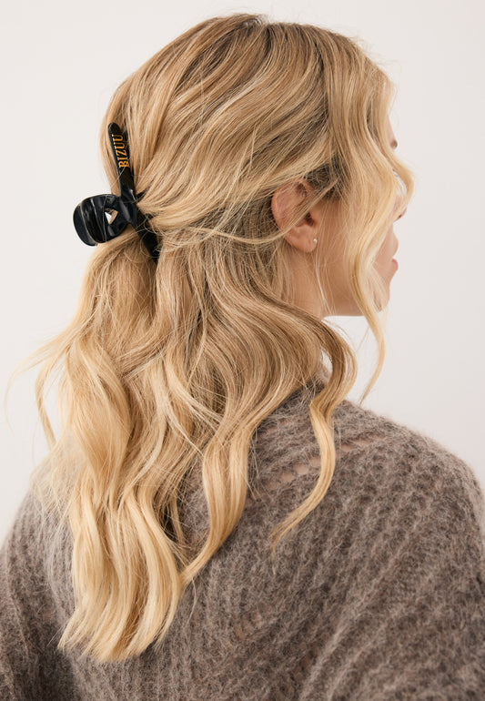 Close-up of the model’s hair styled with the black WILDA hair clip featuring the gold BIZUU logo.