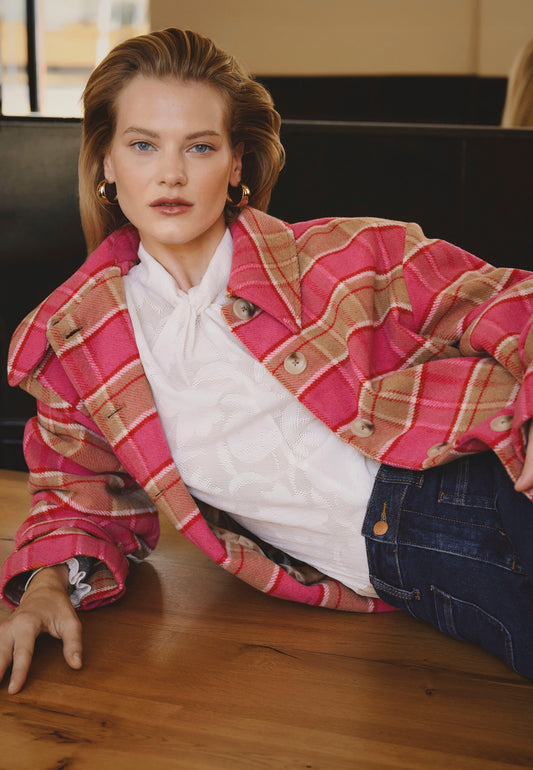 A model wearing a pink WIVINA checked coat with a logo on the sleeve.