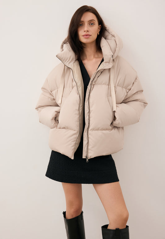 Smiling model wearing the black YOKO down jacket with branded drawstrings.