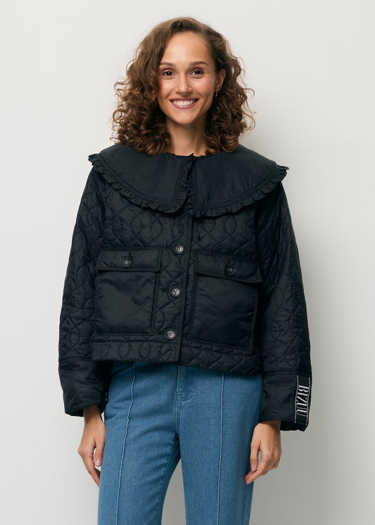 A smiling model wearing a black ZANNI jacket with a detachable collar.