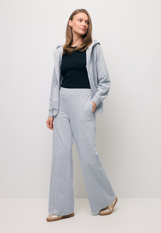 The model wearing a grey tracksuit set – PETRAS wide-leg sweatpants and an IANELLA zip-up hoodie.