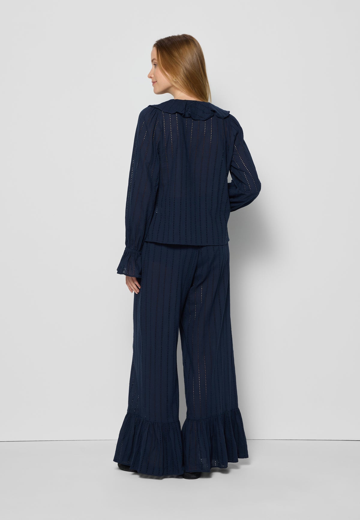 Model standing backwards in a navy blue English embroidery set of PROVANCE blouse and LAVENDOU pants.