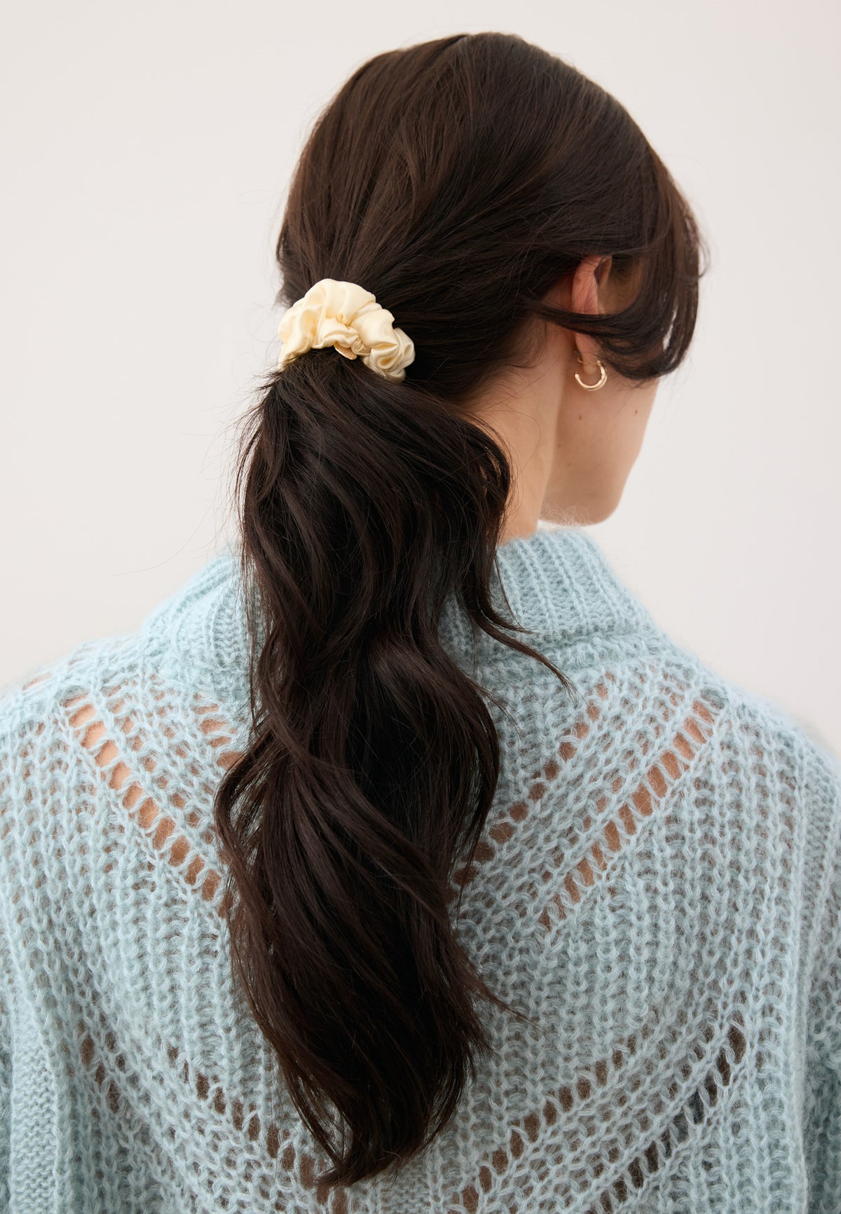 Model’s hair tied in a ponytail with the cream ALLY silk scrunchie.