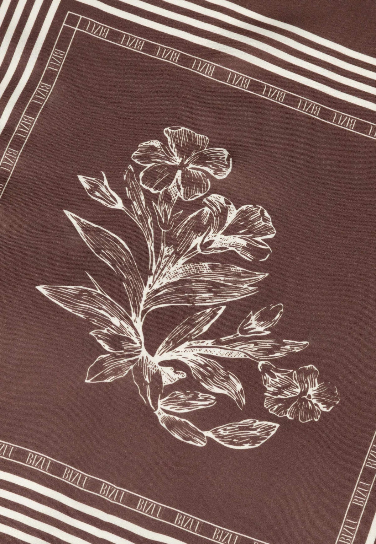 Floral pattern detail at the center of the brown ARIA silk scarf.
