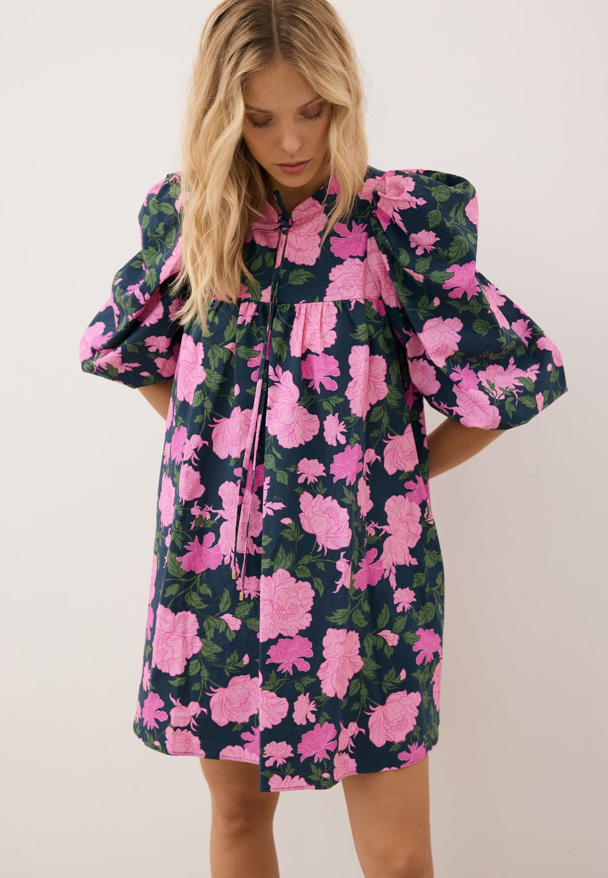 The front of the mini dress features a floral print by AYOTE and a loose fit.