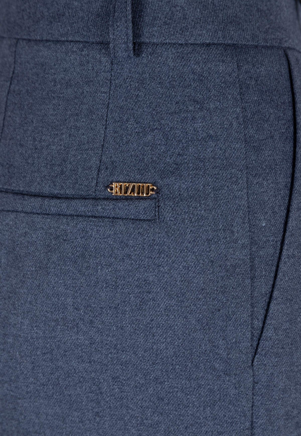 Close-up of the golden logo above the imitation pocket on the back of the navy BANOS trousers.
