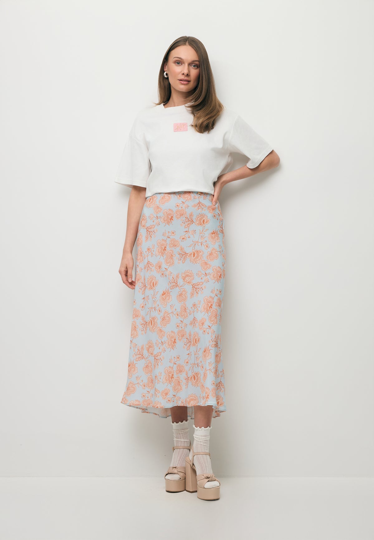 A model wearing the white PARADISO T-shirt and the BREE viscose midi skirt.