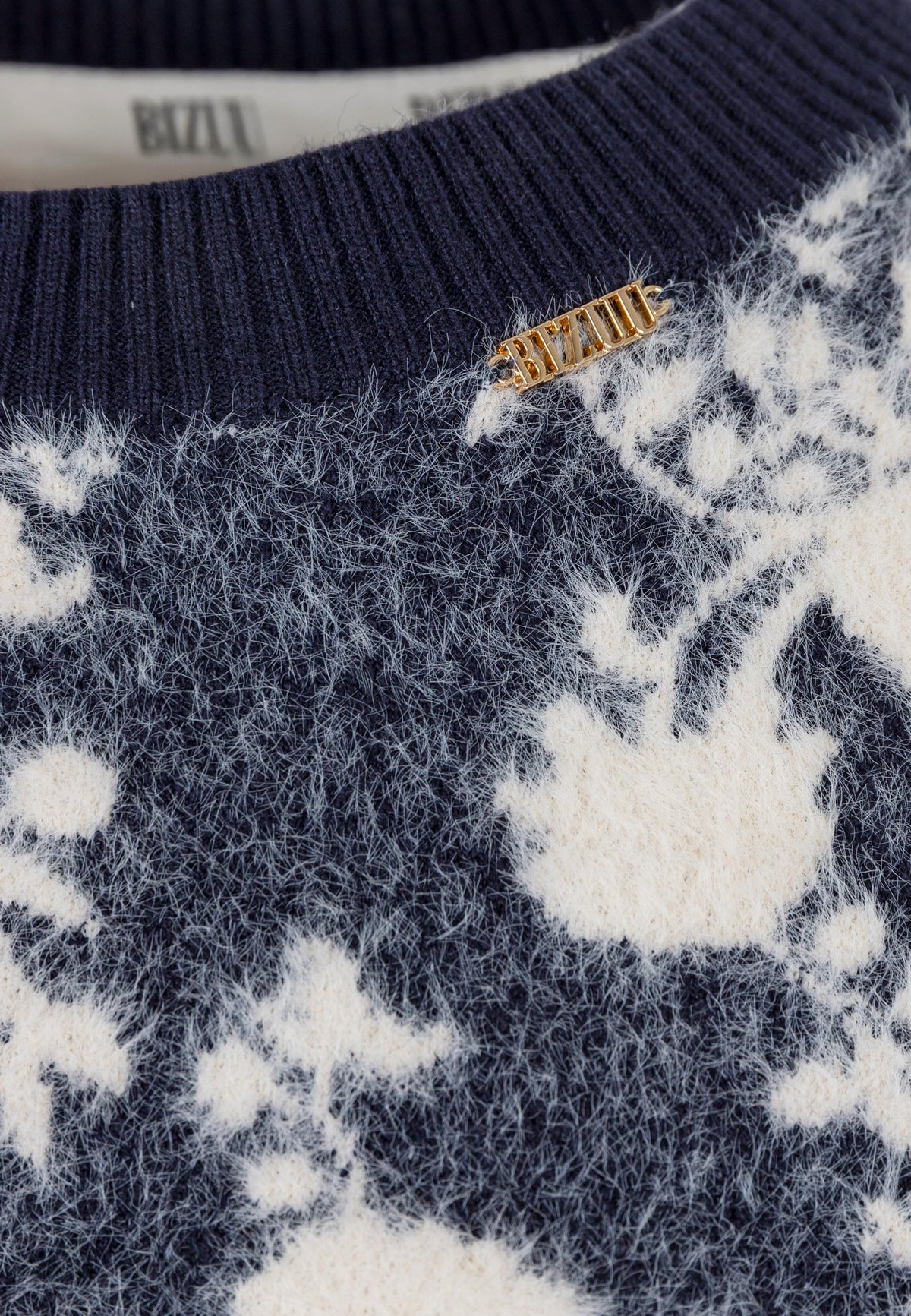 Close-up of the gold logo on the CANELA sweater.