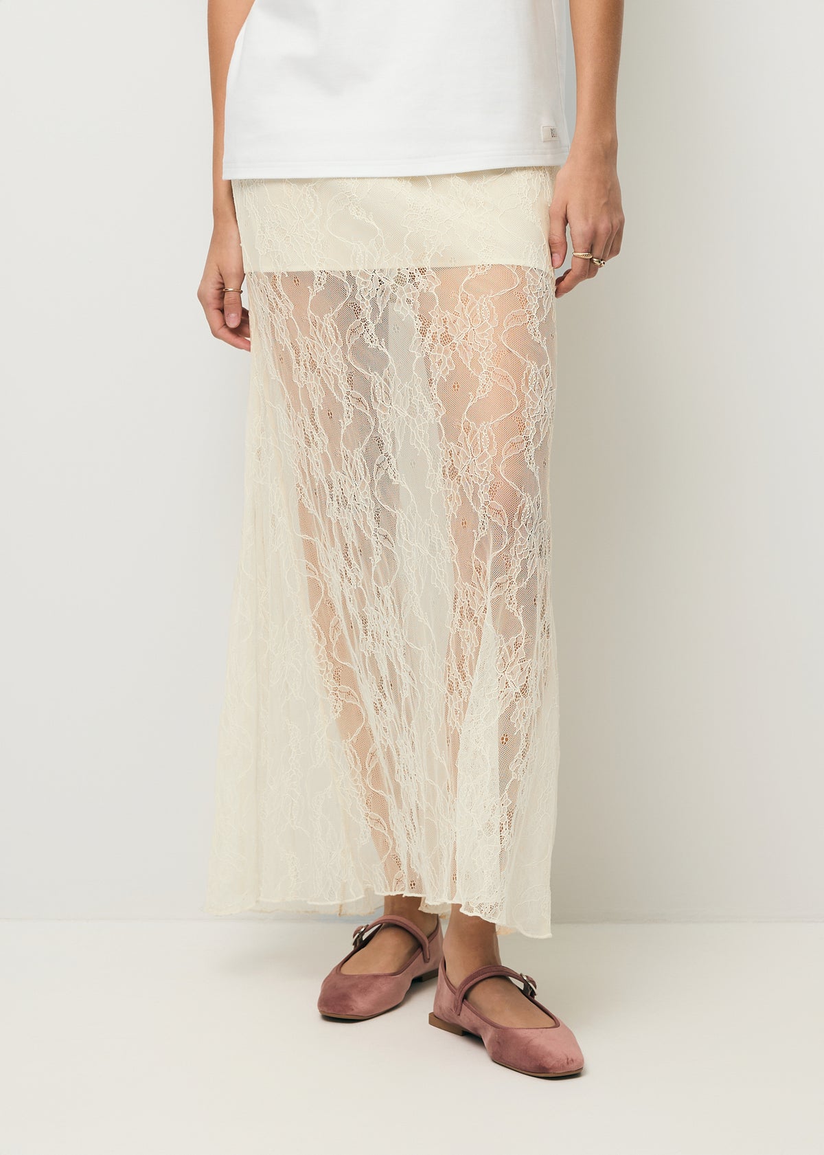 Close-up of the model’s legs in a cream FLACE lace skirt.