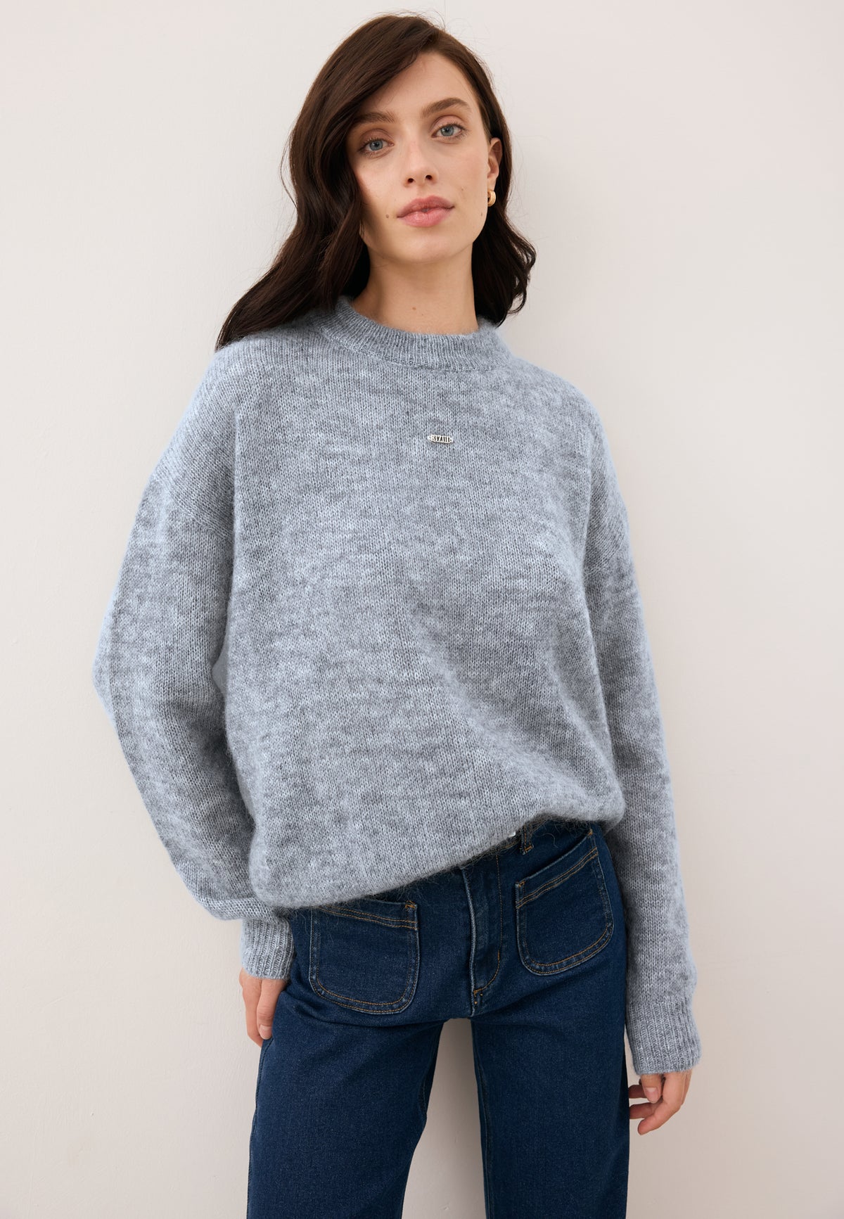 Model wearing the gray wool FAROA sweater with gold logo on the front.