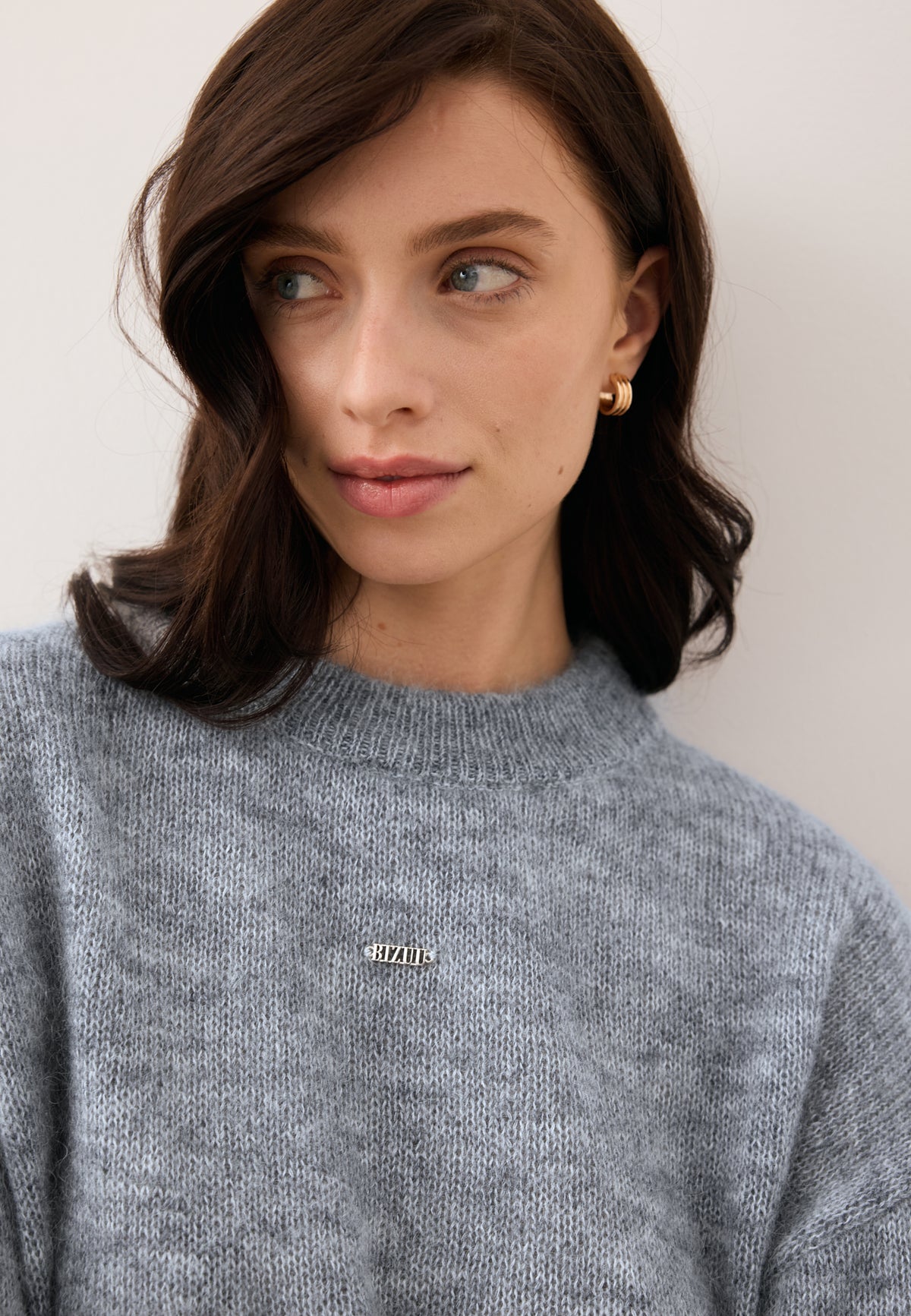 Close-up of the model in the FAROA wool sweater with front logo.