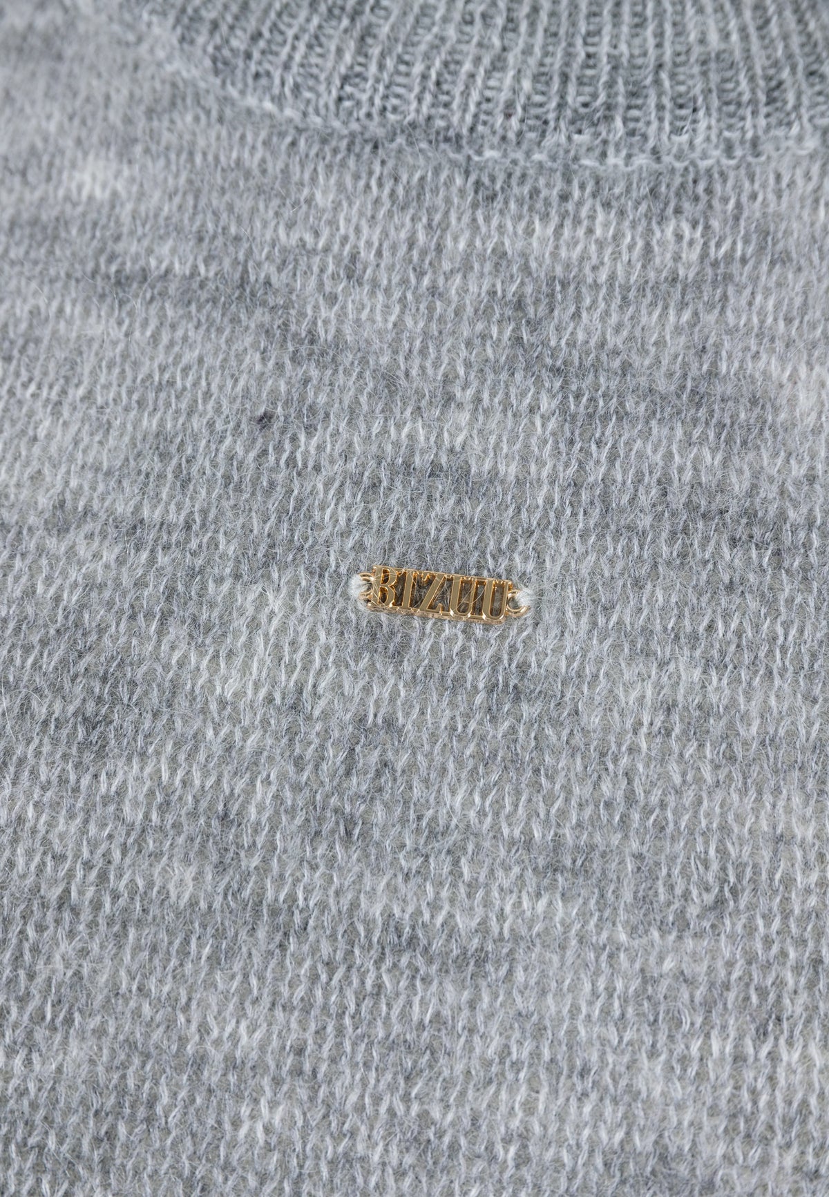 Close-up of the gold logo on the front of the FAROA sweater.