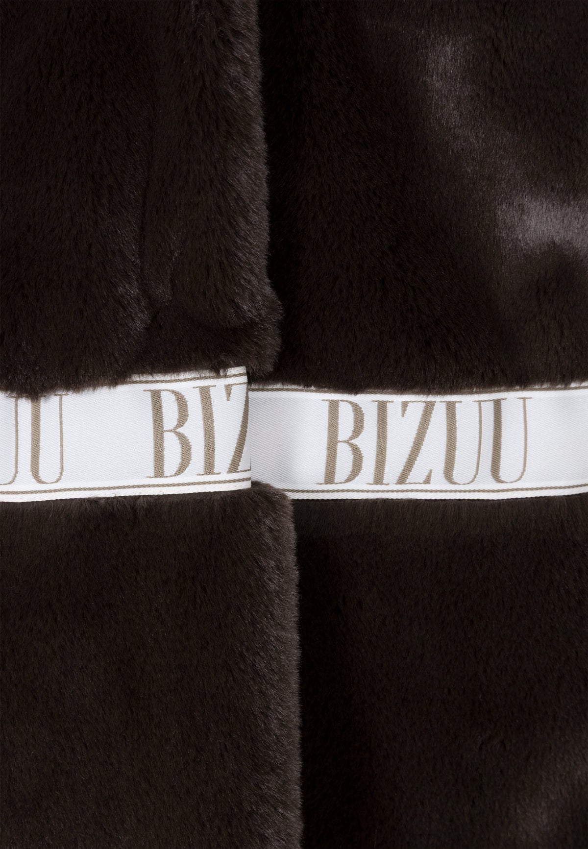 Close-up of the branded logo tape on the brown FLORENCE faux fur coat.