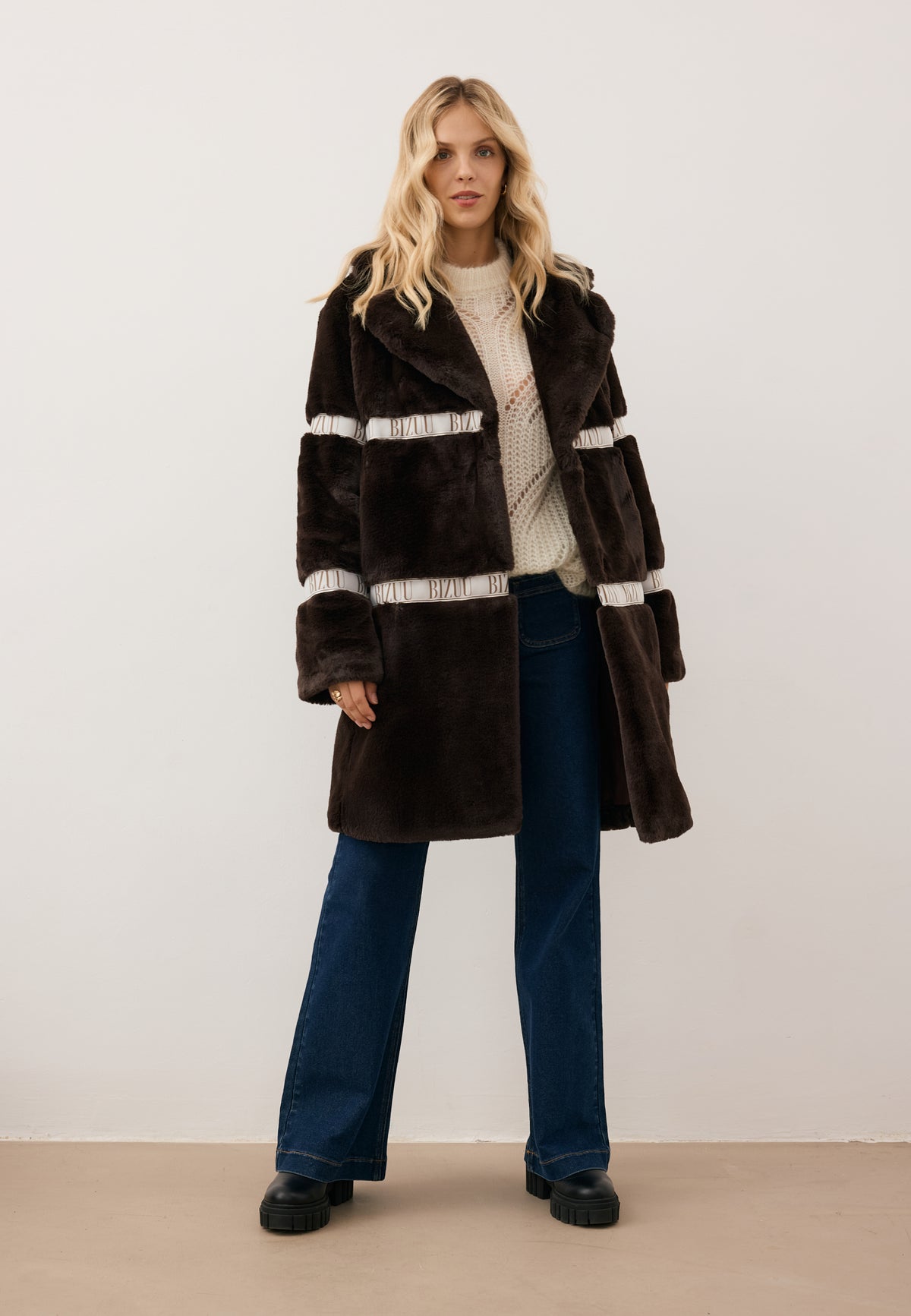 Model moving side to side in the unbuttoned brown FLORENCE faux fur coat with BIZUU logo tape.