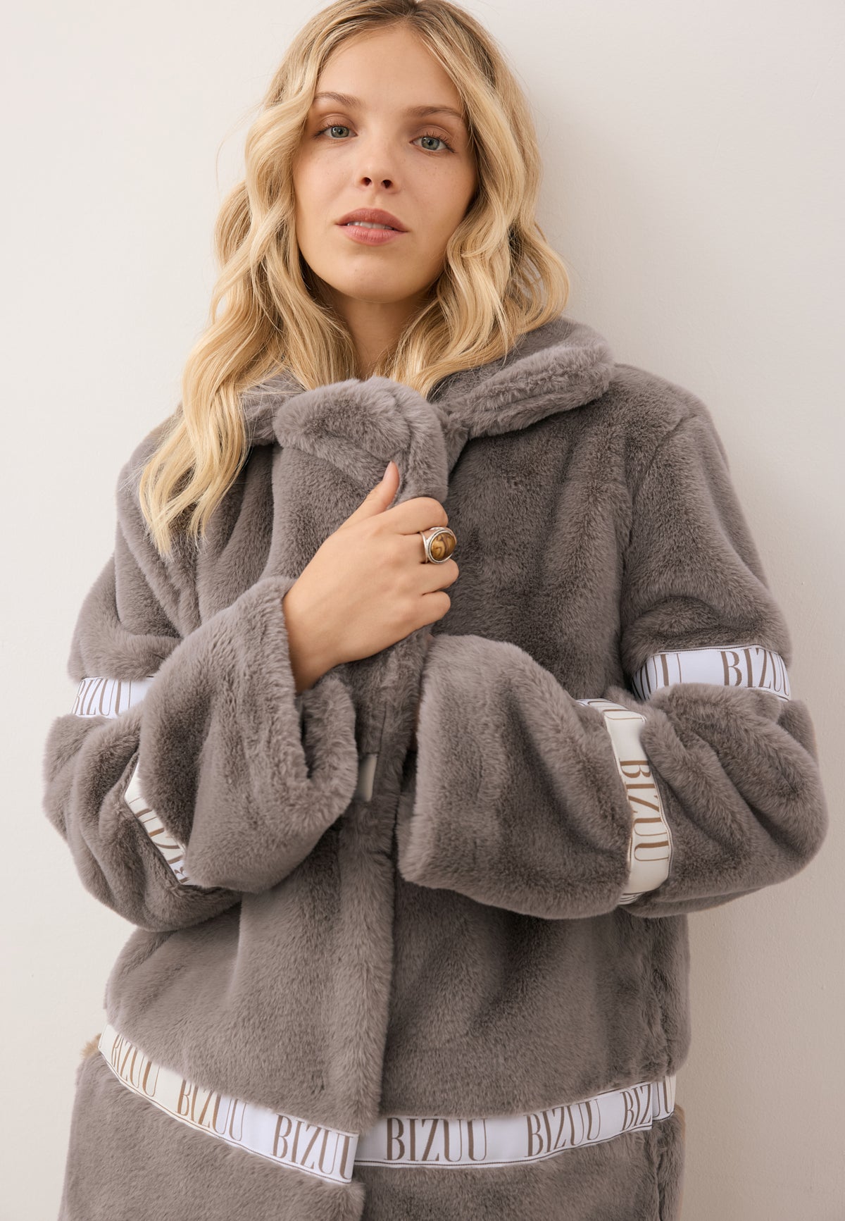 Close-up of the model wrapping herself in the collar of the taupe FLORENCE faux fur coat.