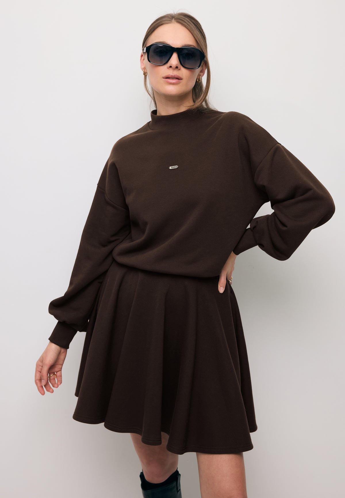 Close-up of a model wearing the brown FOXI knit dress with a flared hem.