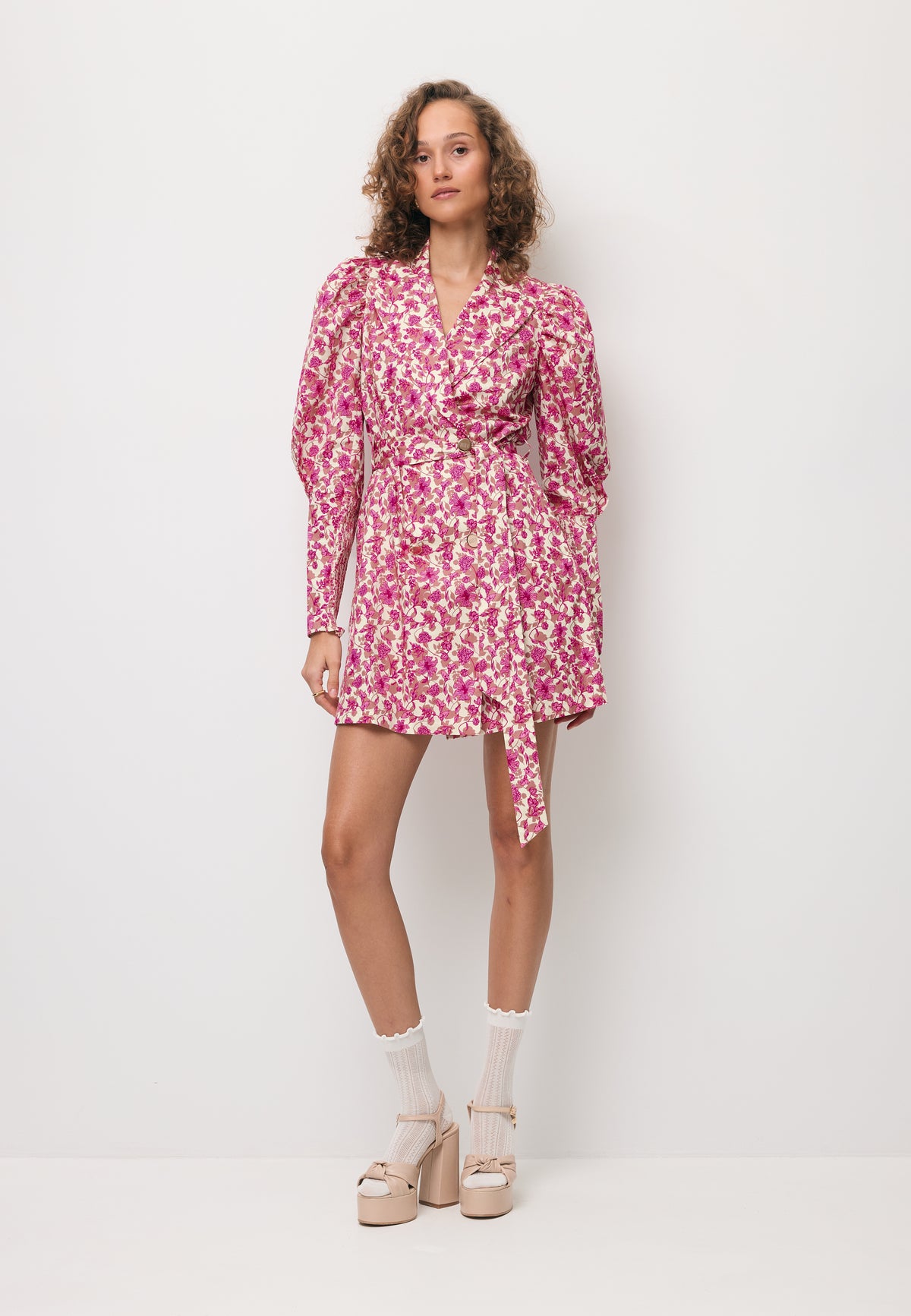 The model wearing the GEORGINA floral mini dress tied at the waist.