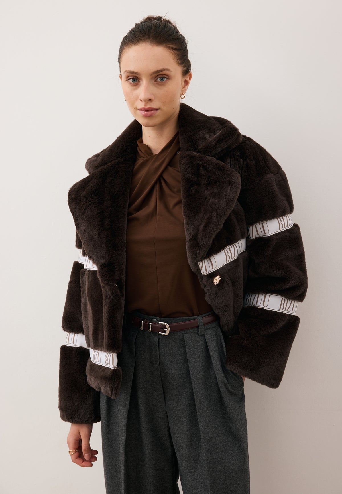 Model facing forward, wearing the short brown GREGORIA faux fur coat unbuttoned.