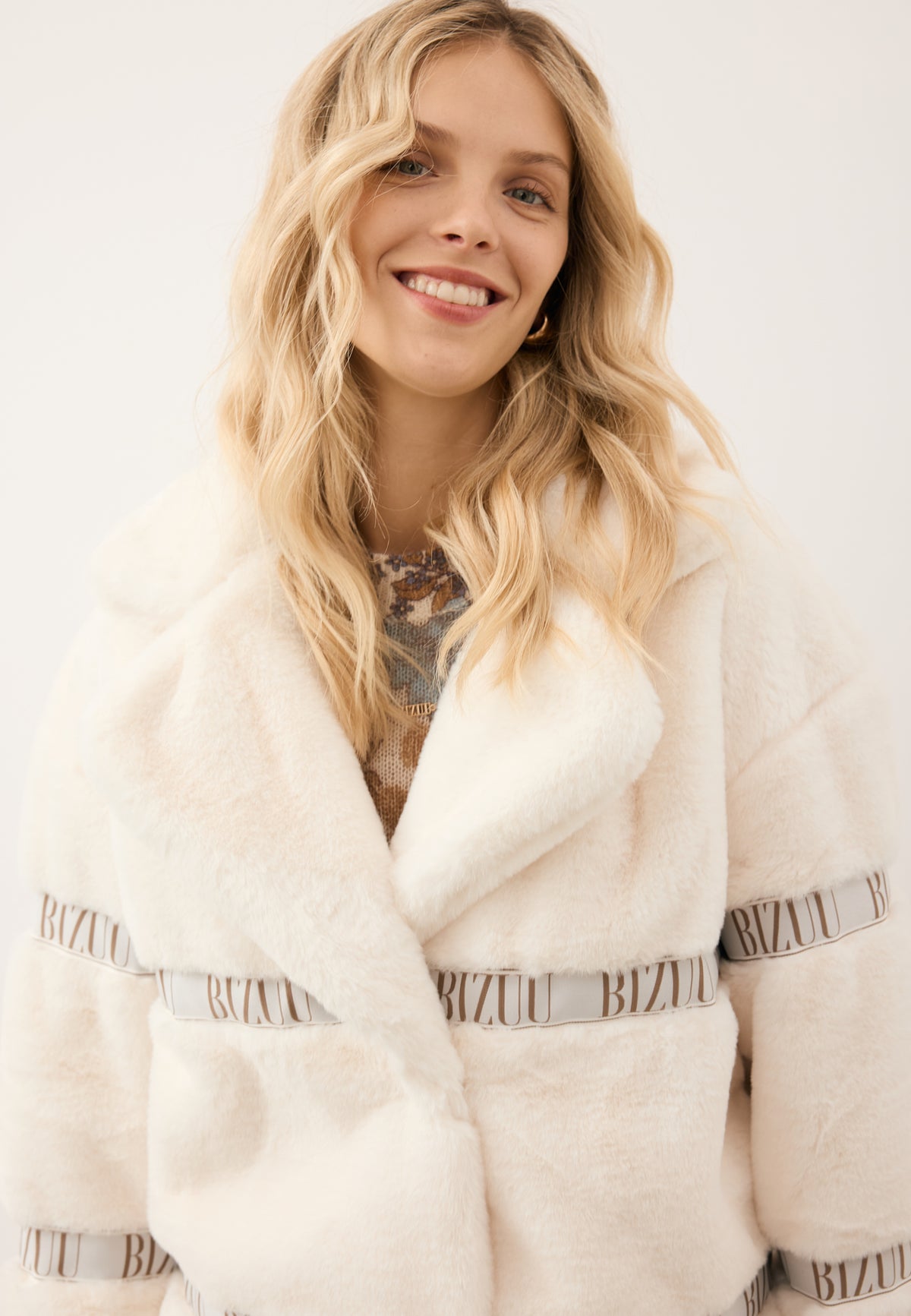 Close-up of the model in the cream GREGORIA coat with a notched collar.
