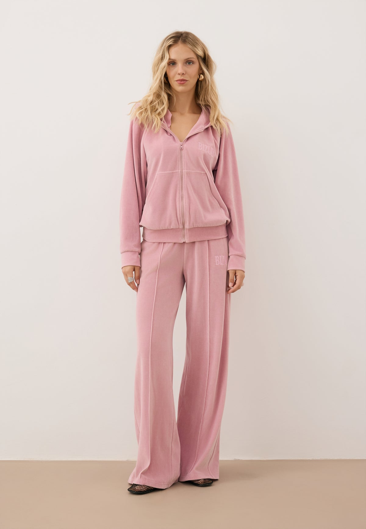 Close-up of a model wearing a pink tracksuit set consisting of an IANELLA sweatshirt and VELORINA pants.