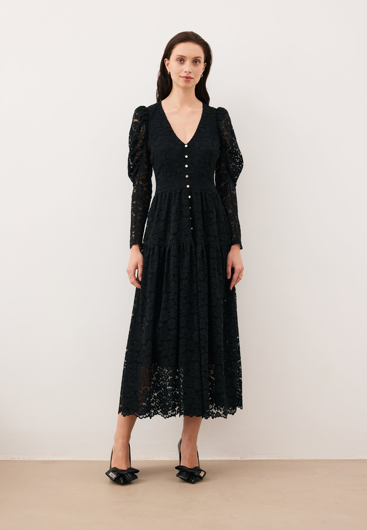 Model standing against a white wall wearing the ISORELLA midi lace dress.