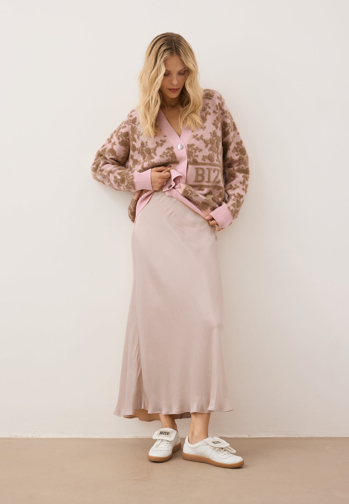 Model slightly lifting the LANZAR cardigan, styled with the satin BREE midi skirt.
