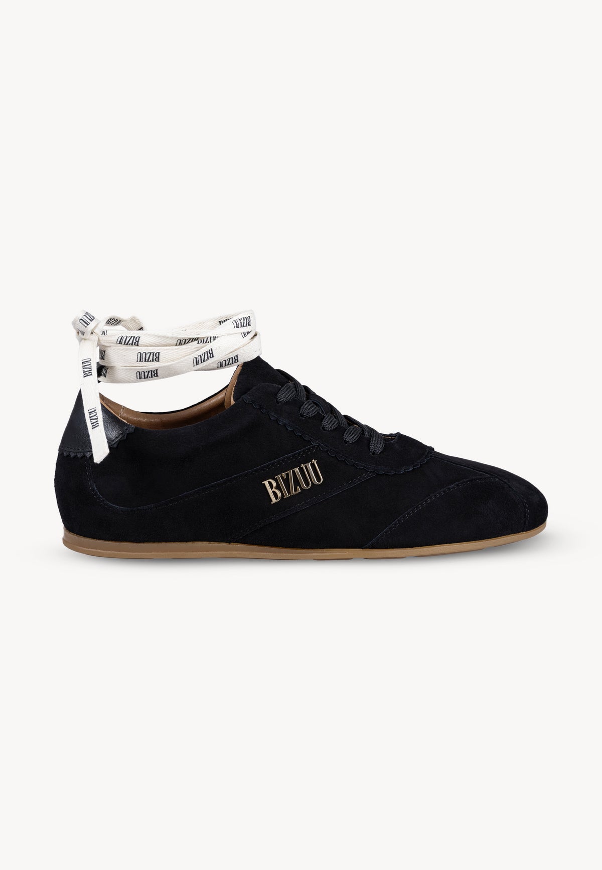 Black LEOLA sneakers standing sideways, with a gold Bizuu logo on the side. The shoe is shown with an additional ribbon with the Bizuu logo, which can be tied around the ankle.