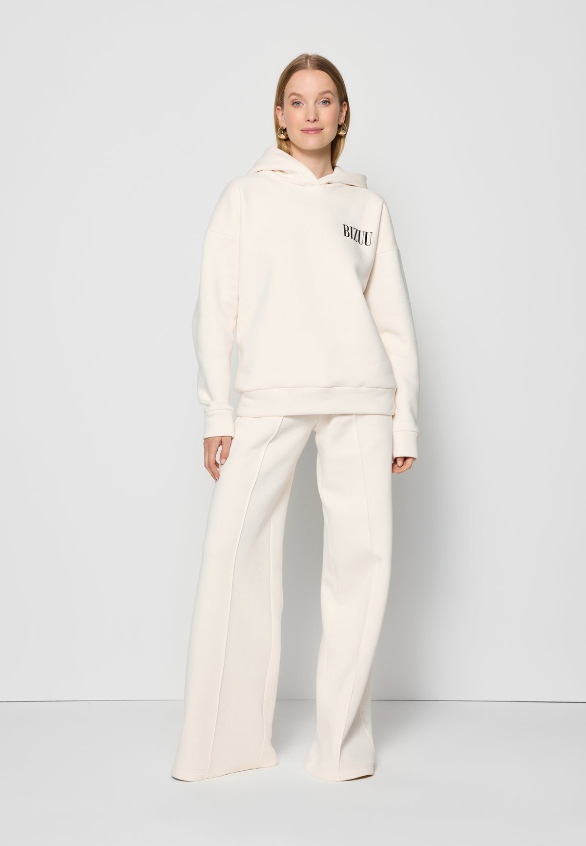 The model on a white background wearing a cream LINDI and PETRA tracksuit set.