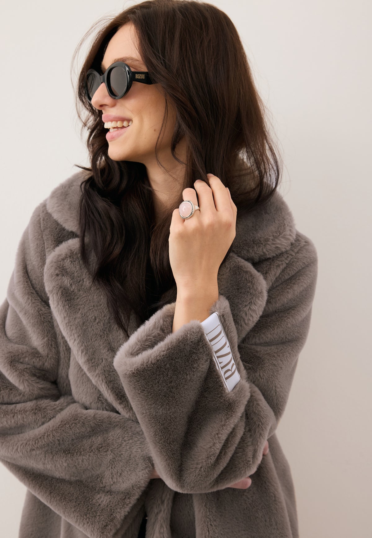 Close-up of the smiling model in the LIVORNO coat with decorative logo patch on the sleeve.
