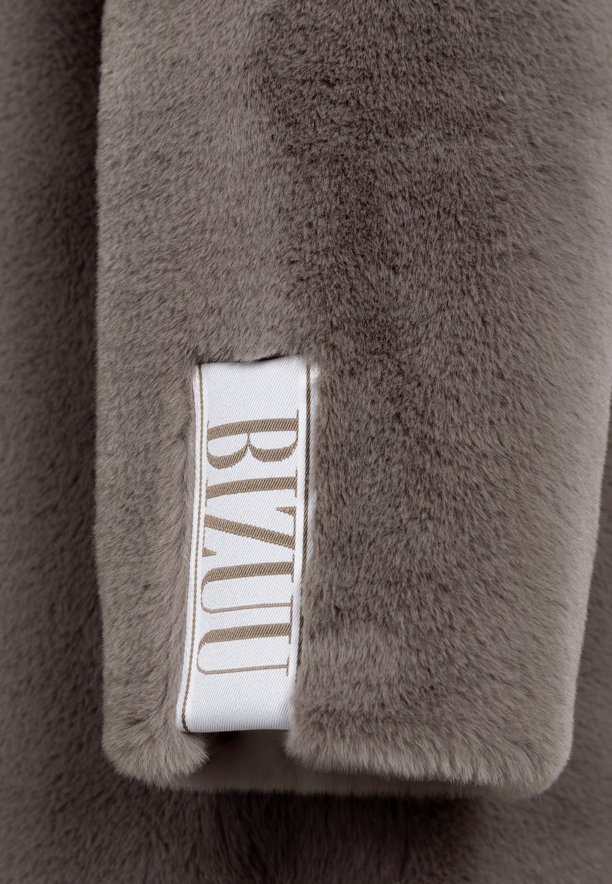 Close-up of the logo tape on the sleeve of the LIVORNO faux fur coat.