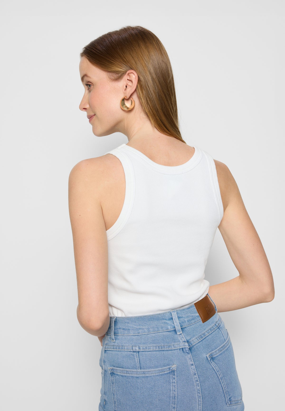 Model standing backwards wearing a white LOVIE top and blue ATLANTA jeans.