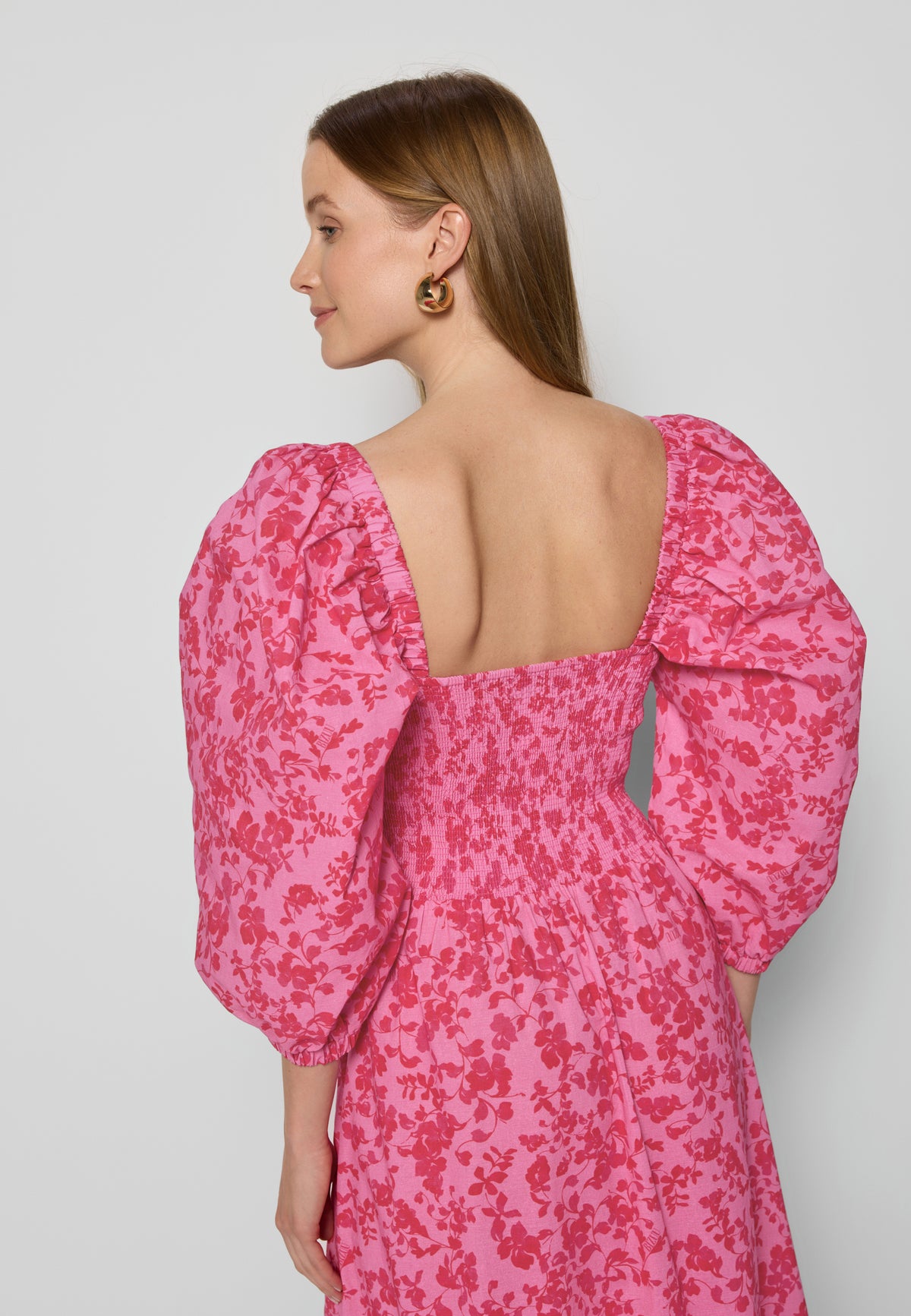Model in dress with open back and buff sleeves, profile view.