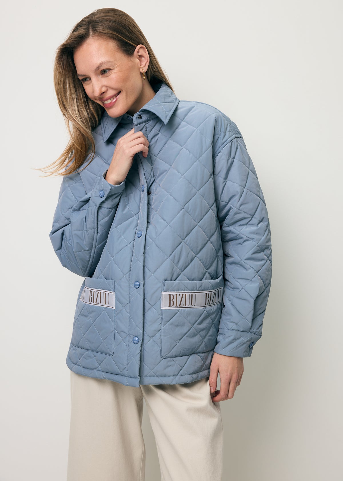 A smiling model wearing the light blue MARIN jacket with logo tape.