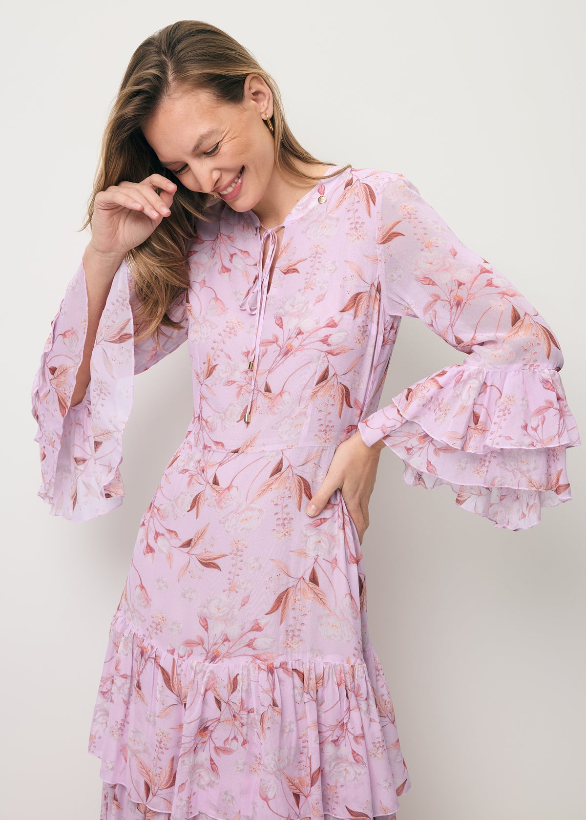 Close-up of a model showcasing the decorative sleeves on the pink MASSI dress.