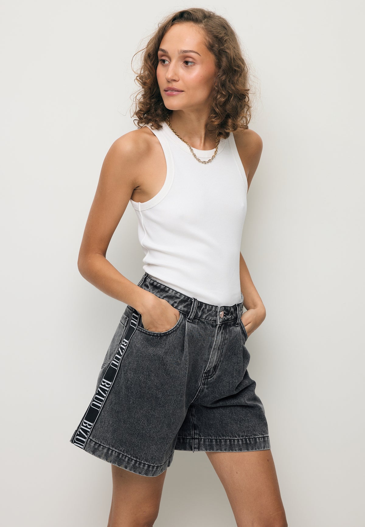 A model wearing black MIREYA denim shorts with a logo tape on the side.