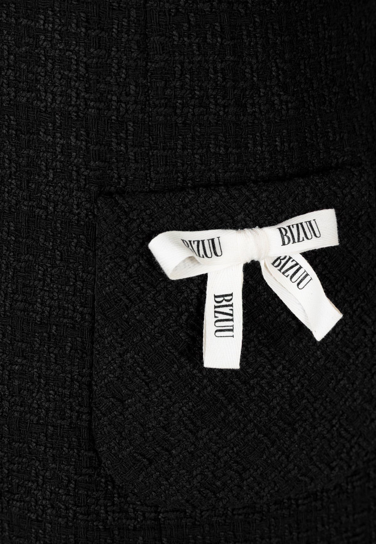Close-up of the branded bow details on the front of the NOILLY dress.