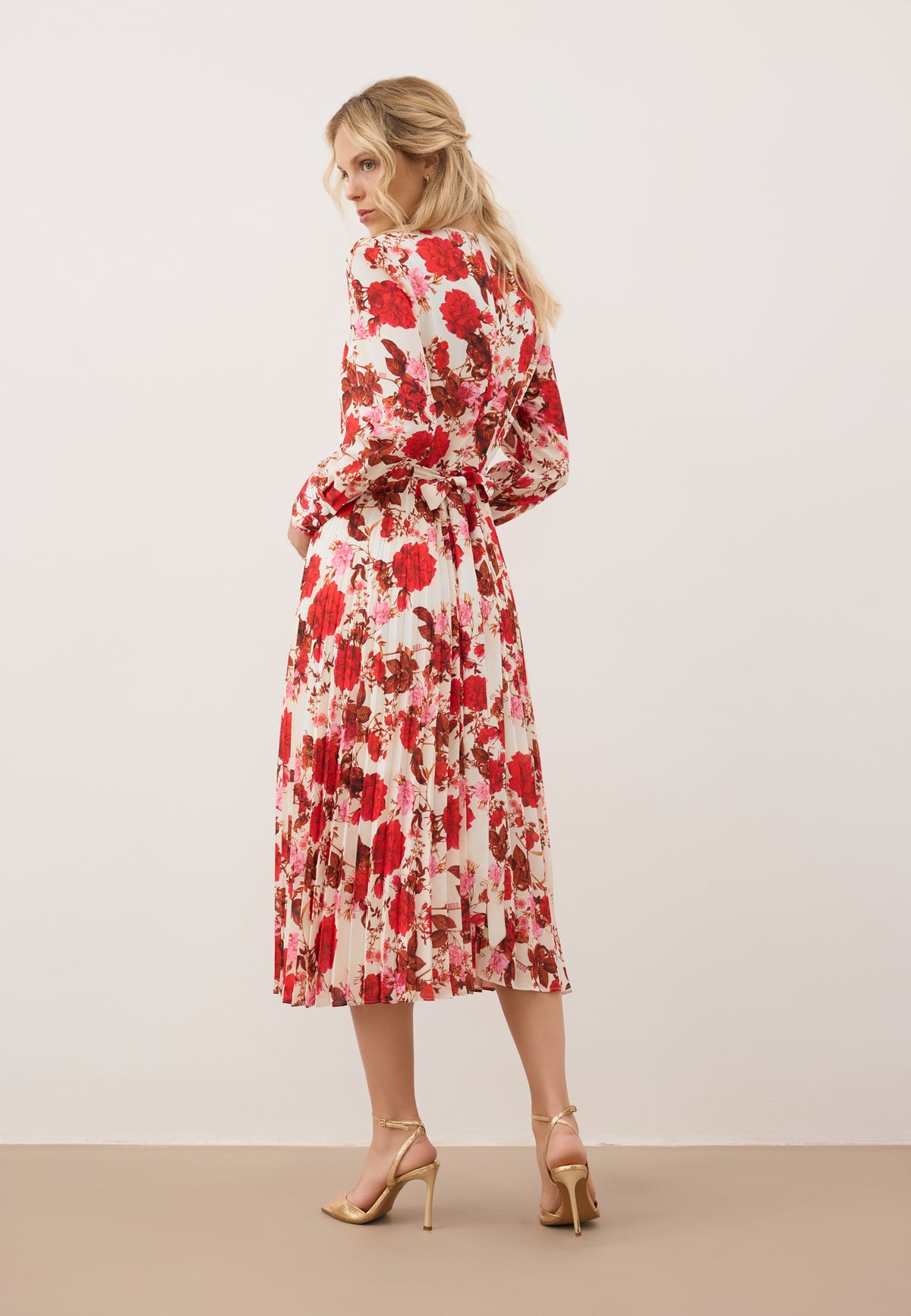Model standing with her back to the camera in a NYLA midi dress with a floral print.
