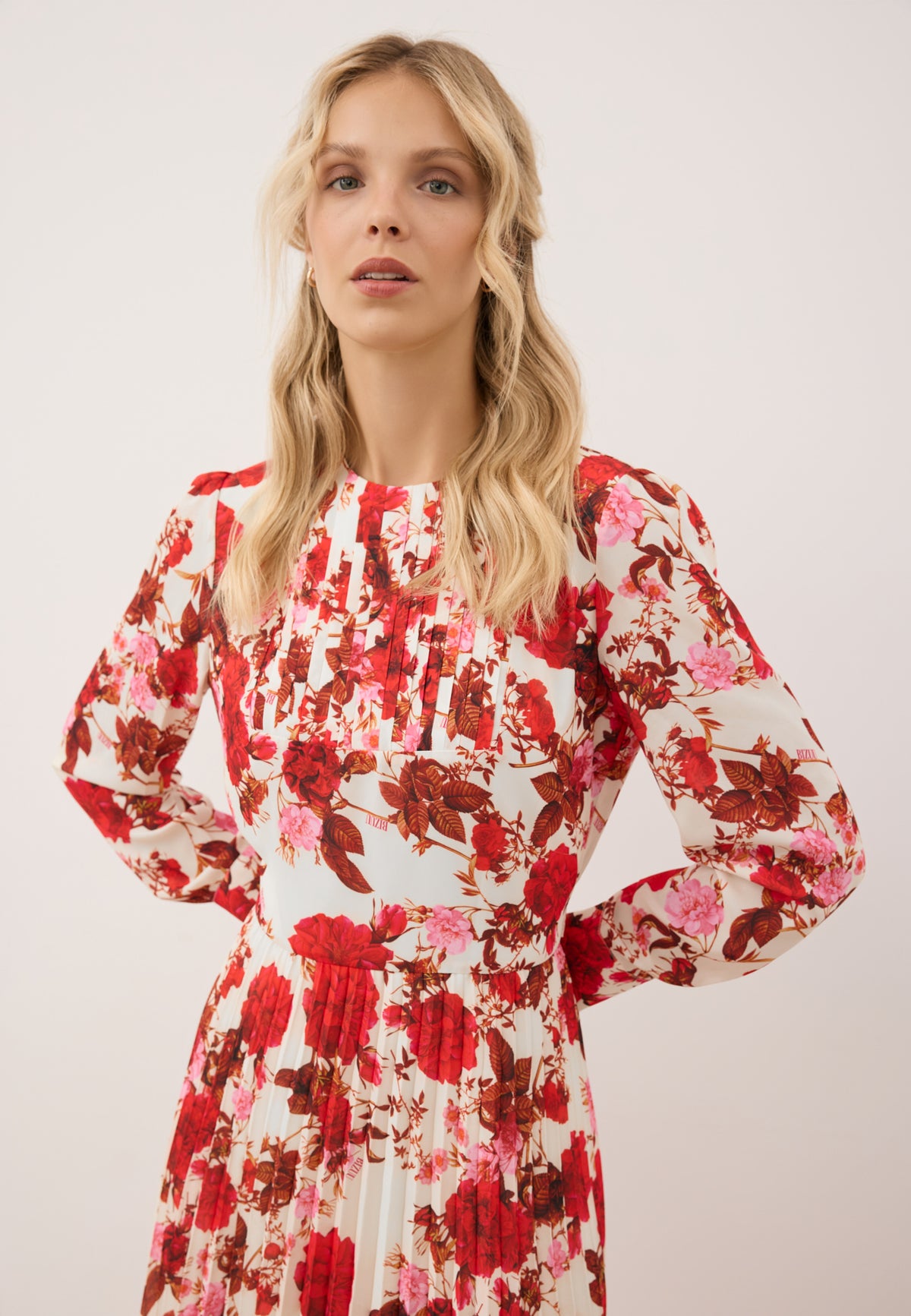 Close-up of a model wearing the NYLA dress. Dress with pleats at the neckline and floral print.